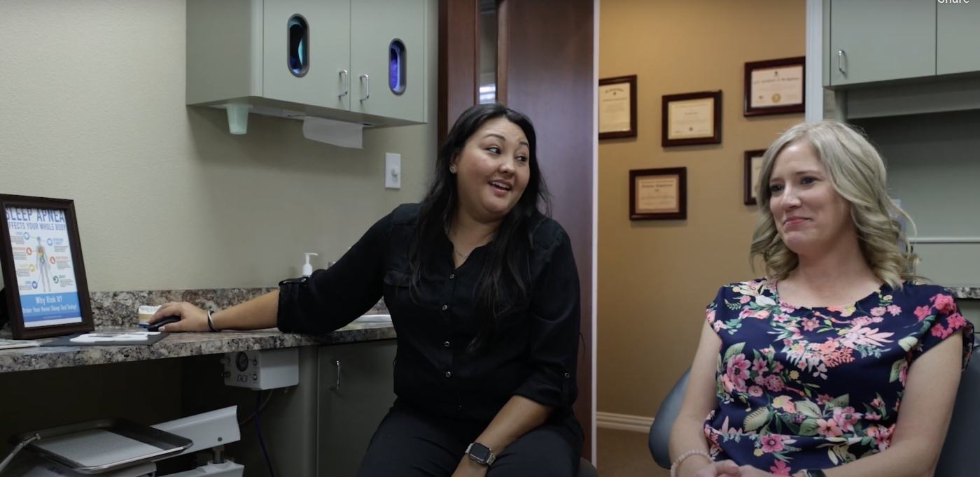 Dental team member talking to a woman in the dental chair