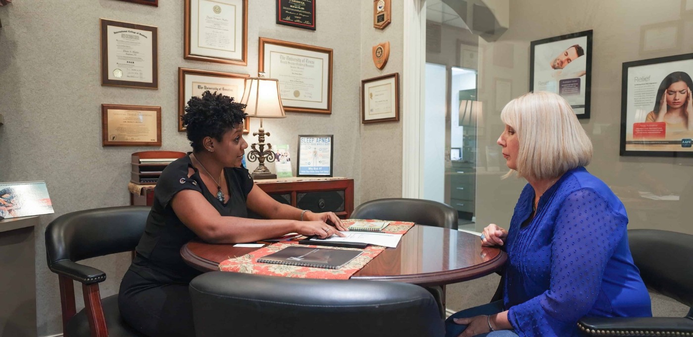 Dental team member sitting across desk from a patient at a consultation