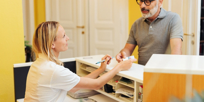 A man paying a dental receptionist