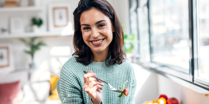 Woman smiling while eating healthy meal at home
