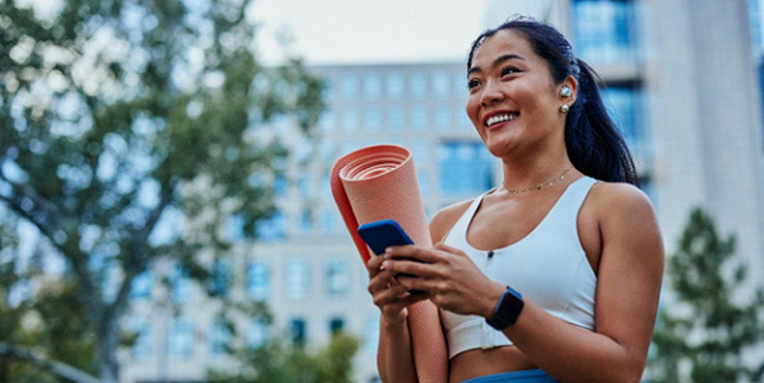 Smiling woman walking on park with workout mat