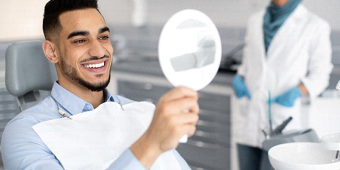 Man smiling at reflection in mirror in treatment chair